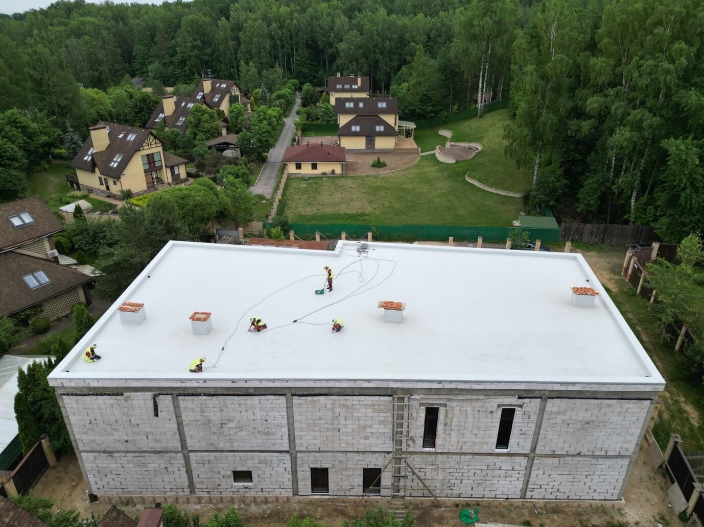 Монтаж ПВХ-мембраны на плоской кровле частного дома, вид с дрона