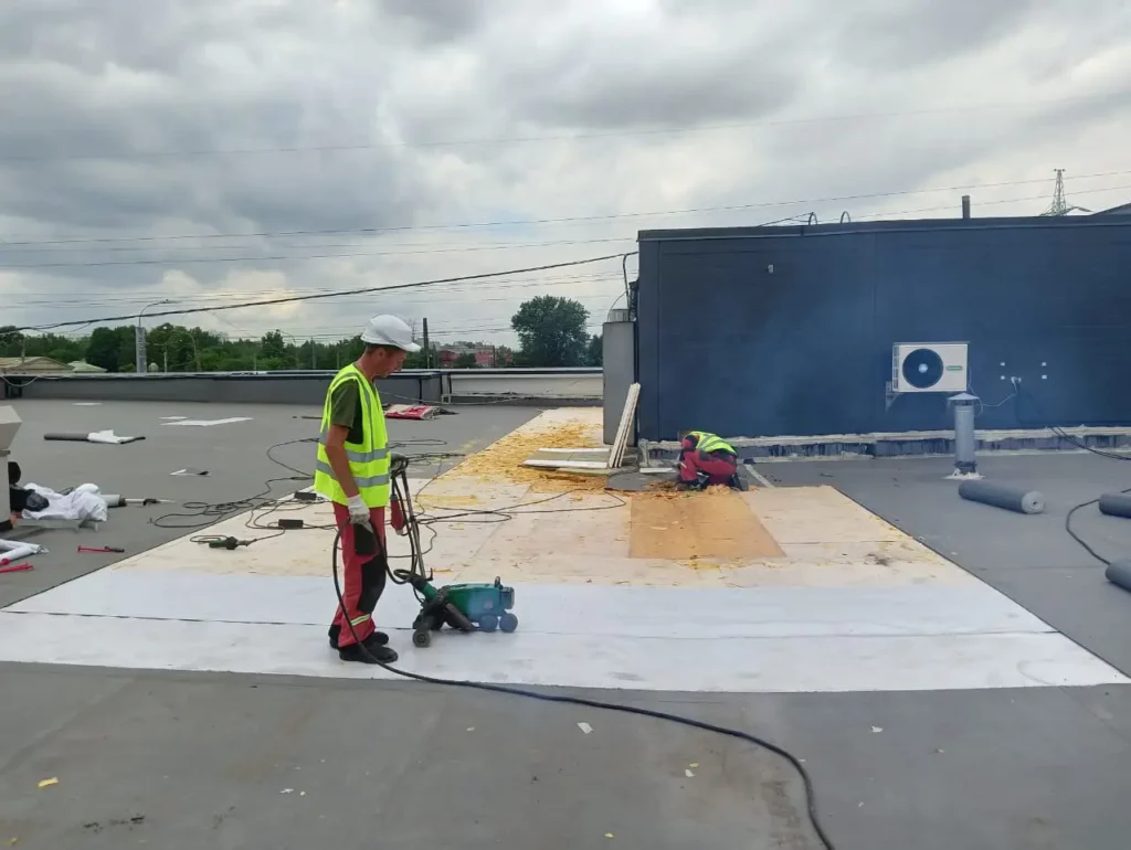 Сварка ПВХ-мембраны на кровле автосервиса в Санкт-Петербурге — мастер АНКОНС работает с автоматическим аппаратом